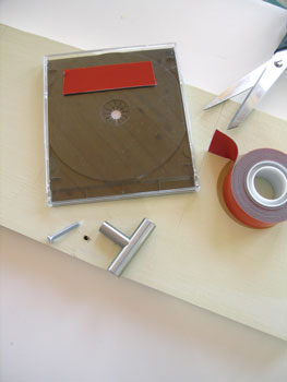 2. Cut a 1-inch by 8-inch board about 42 inches long. Paint or stain as desired. Exterior-grade mounting tape works well to attach the jewel cases to the board because it is strong and resists water. Space the jewel cases evenly down the length of the board, leaving extra space on either end.